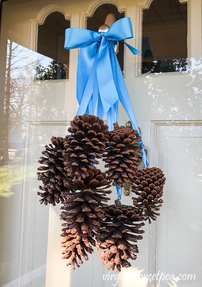 Winter door decor with pine cones hanging from satin ribbon