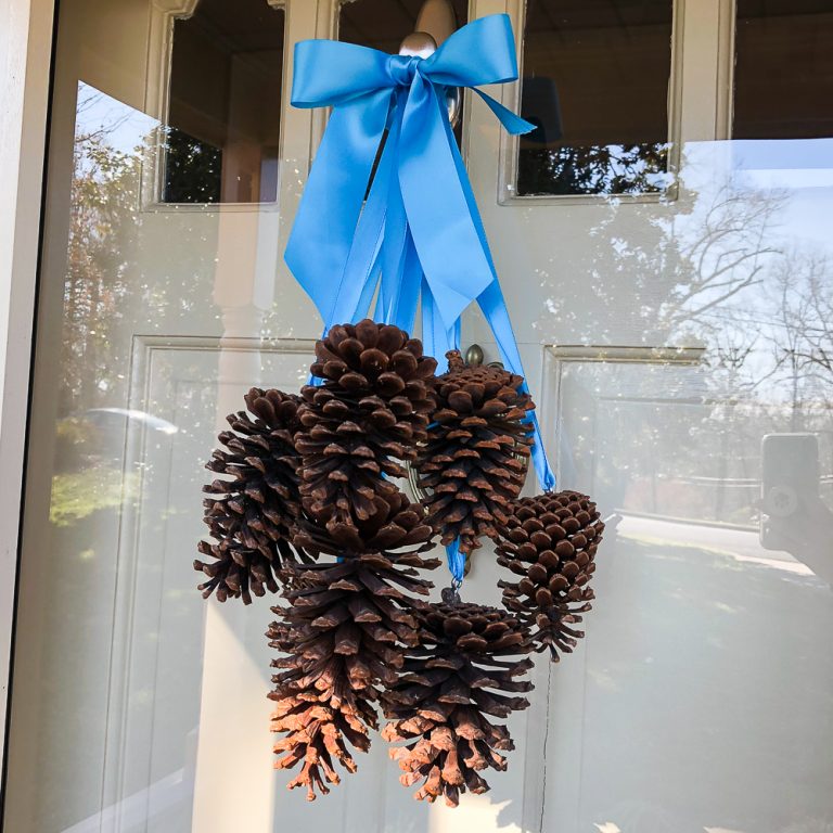 Pine cone door decoration - pine cones hanging from ribbons on a front door.