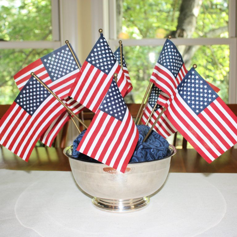 Small American flags displayed in a silver bowl with blue fabric