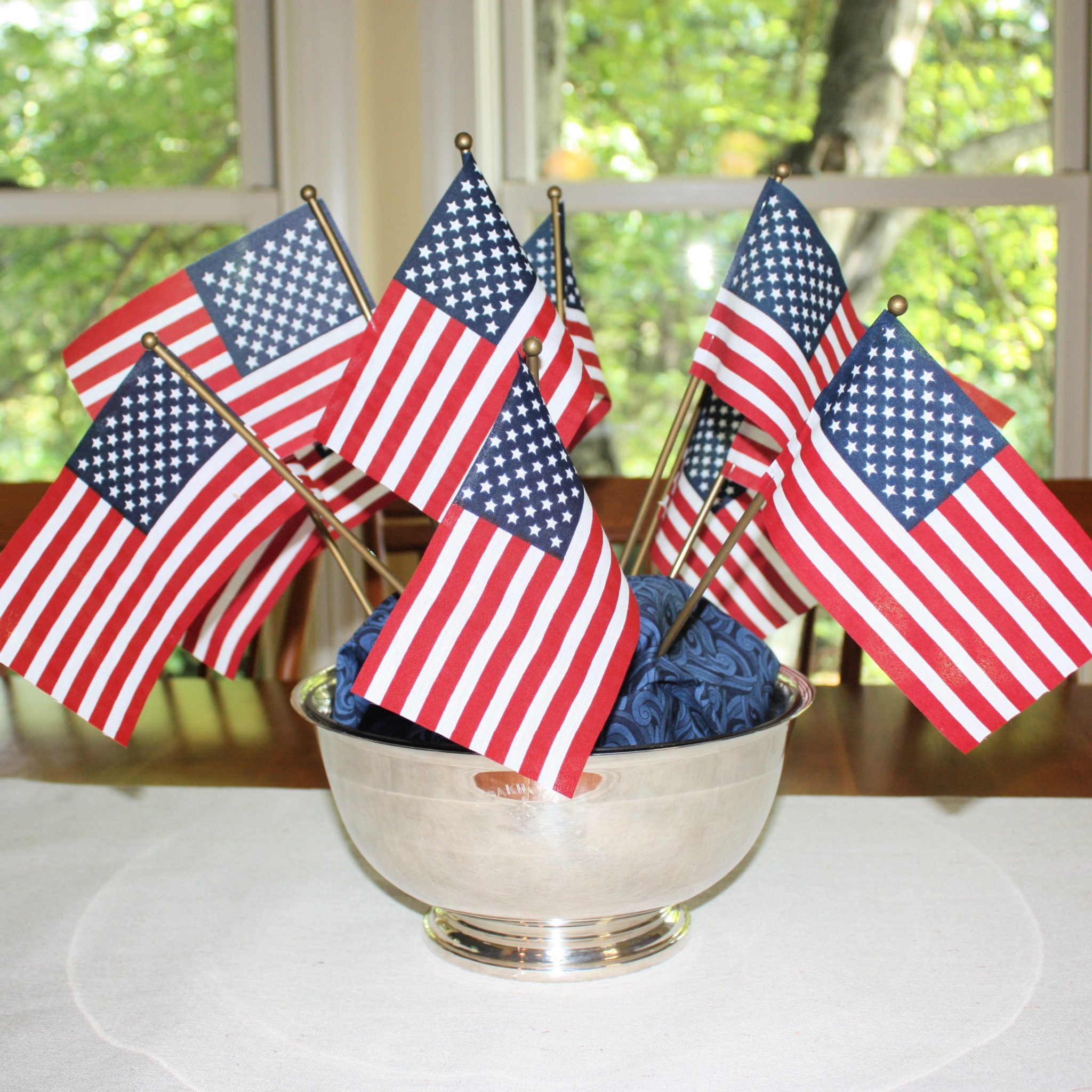 Small American flags displayed in a silver bowl with blue fabric