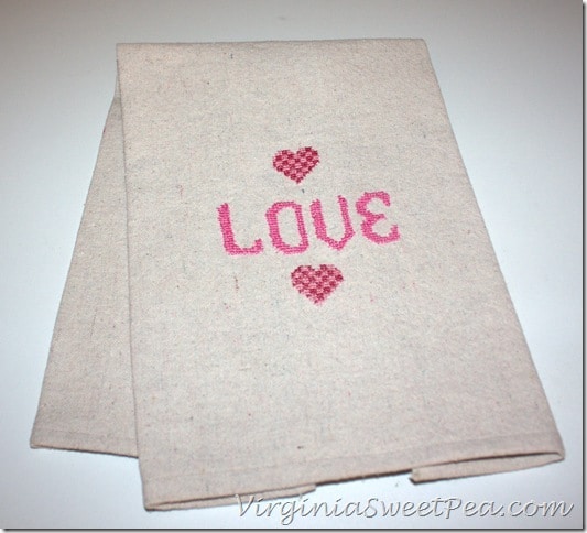 DIY Cross Stitch Valentine's Day Towel - Make this cute tea towel using a drop cloth scrap.  It looks so cute hanging on the stove in the kitchen or on display in a bathroom.  virginiasweetpea.com  #crossstitch #valentinesday #valentinesdaycraft