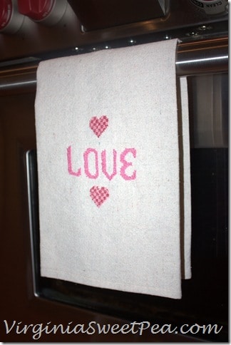 DIY Cross Stitch Valentine's Day Towel - Make this cute tea towel using a drop cloth scrap.  It looks so cute hanging on the stove in the kitchen or on display in a bathroom.  virginiasweetpea.com  #crossstitch #valentinesday #valentinesdaycraft