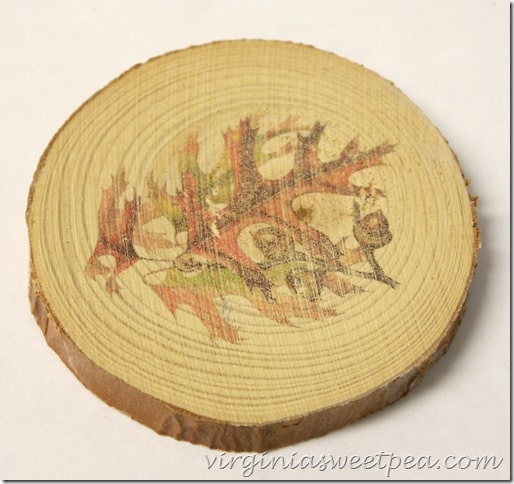 Wood slice with a leaf and acorn image on it.