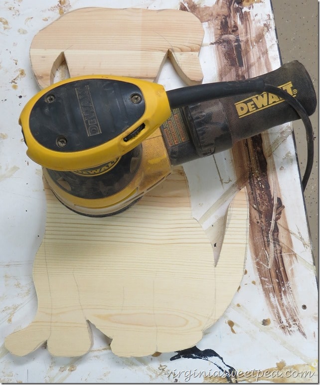 Use a palm sander and regular sandpaper to sand the dog.