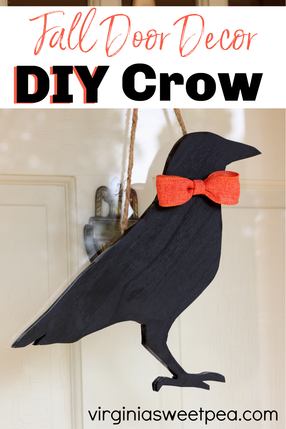 Wooden cutout crow painted black with an orange bow hanging on a door.