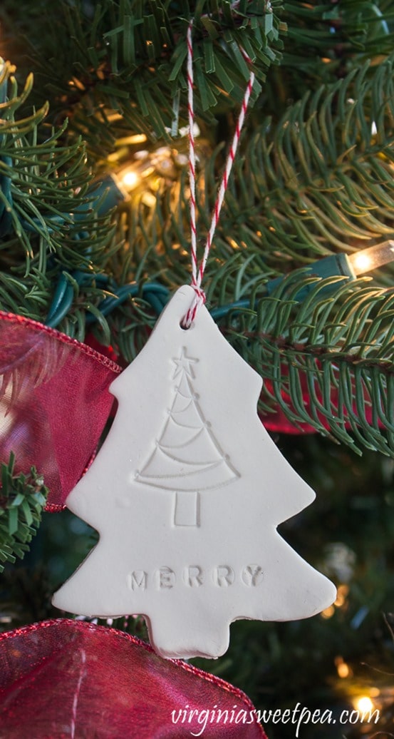 Christmas ornament made from clay in the shape of a Christmas tree with a tree stamp and the word merry.