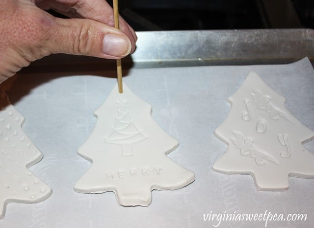 Using a skewer to make a hole in a clay Christmas ornament