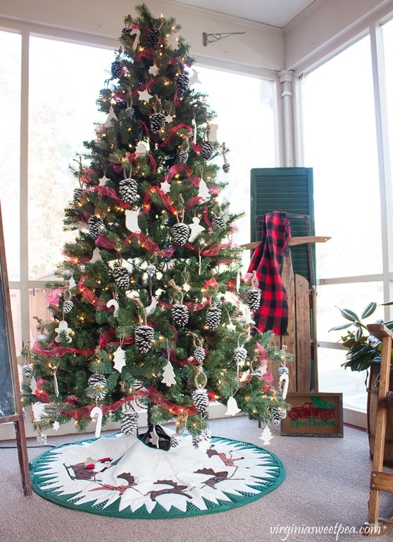 Christmas tree decorated with pine cones, clay ornaments, and red ribbon