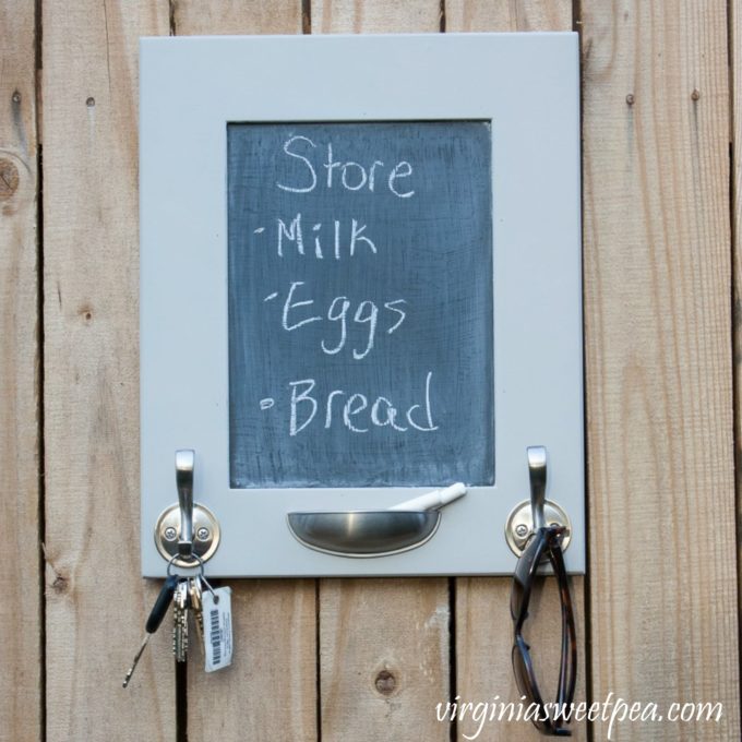 DIY Message Board and Organizer - A cabinet door is upcycled into a message board. Hooks organize keys, sunglasses, hats, dog leashes and anything else you need to keep handy.