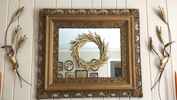 Wheat wreath hanging on a vintage mirror with brash wheat sheaves hanging beside it.