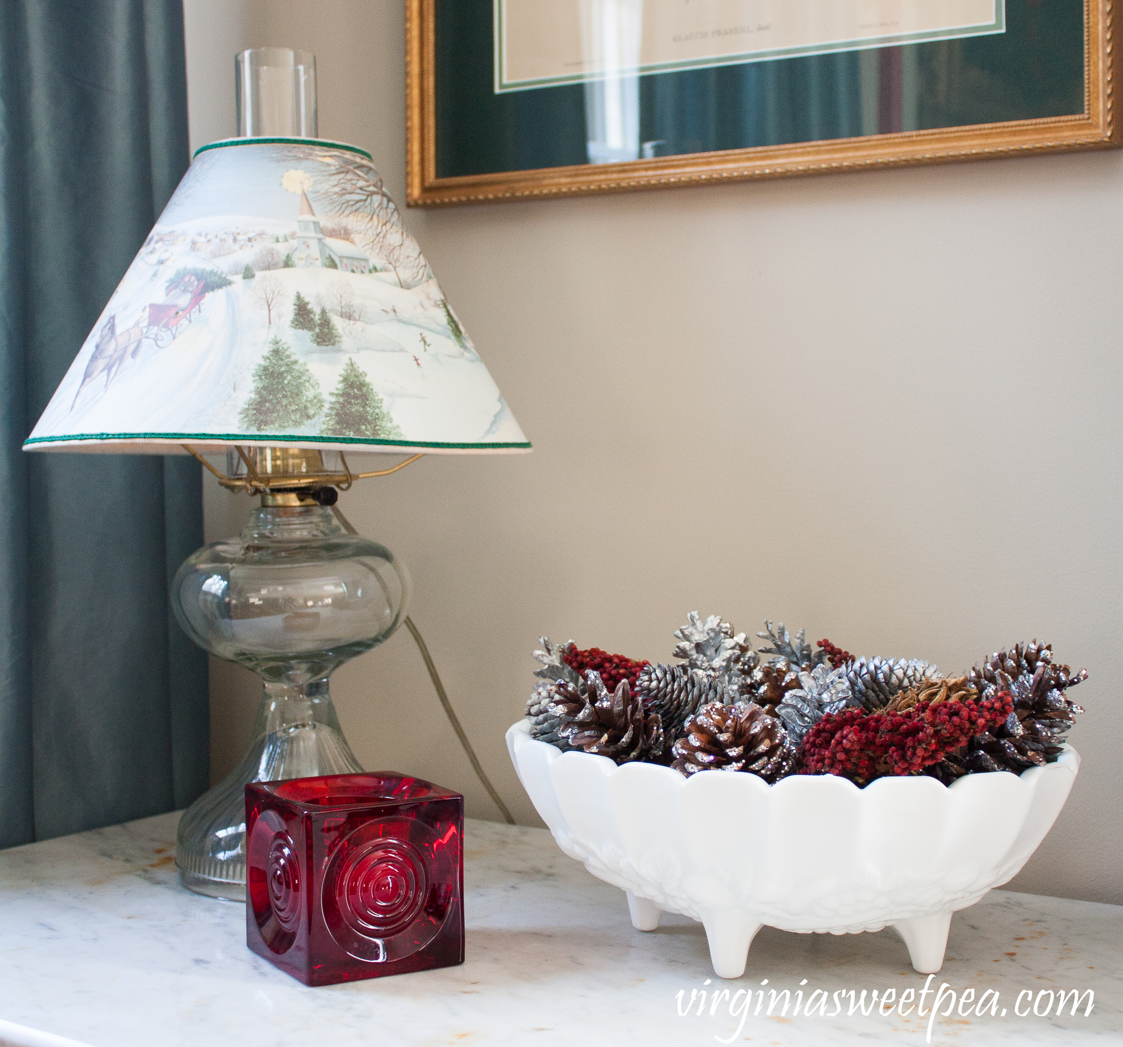 Vintage Christmas Vignette - Antique lamp with a Christmas shade, milk glass compote filled with natural items, and a Blenko candle holder.