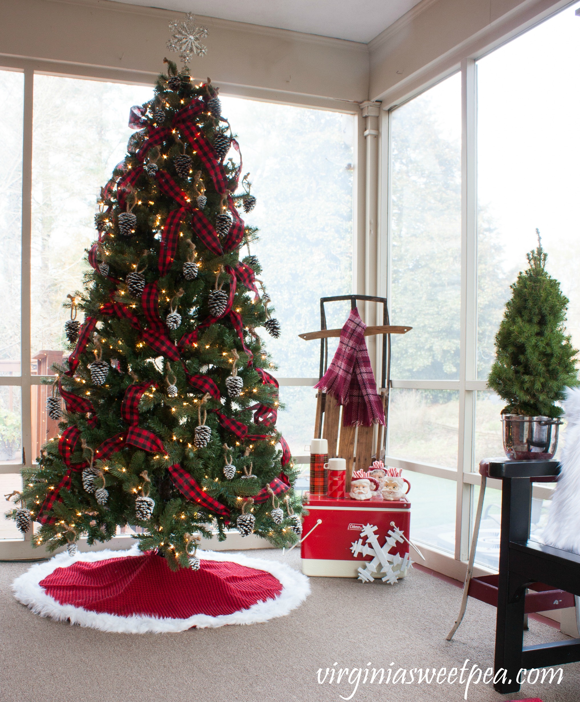 A rustic woodland tree decorates a Christmas porch along with a collection of vintage items. #christmas #christmasdecorations #vintage #vintagechristmas