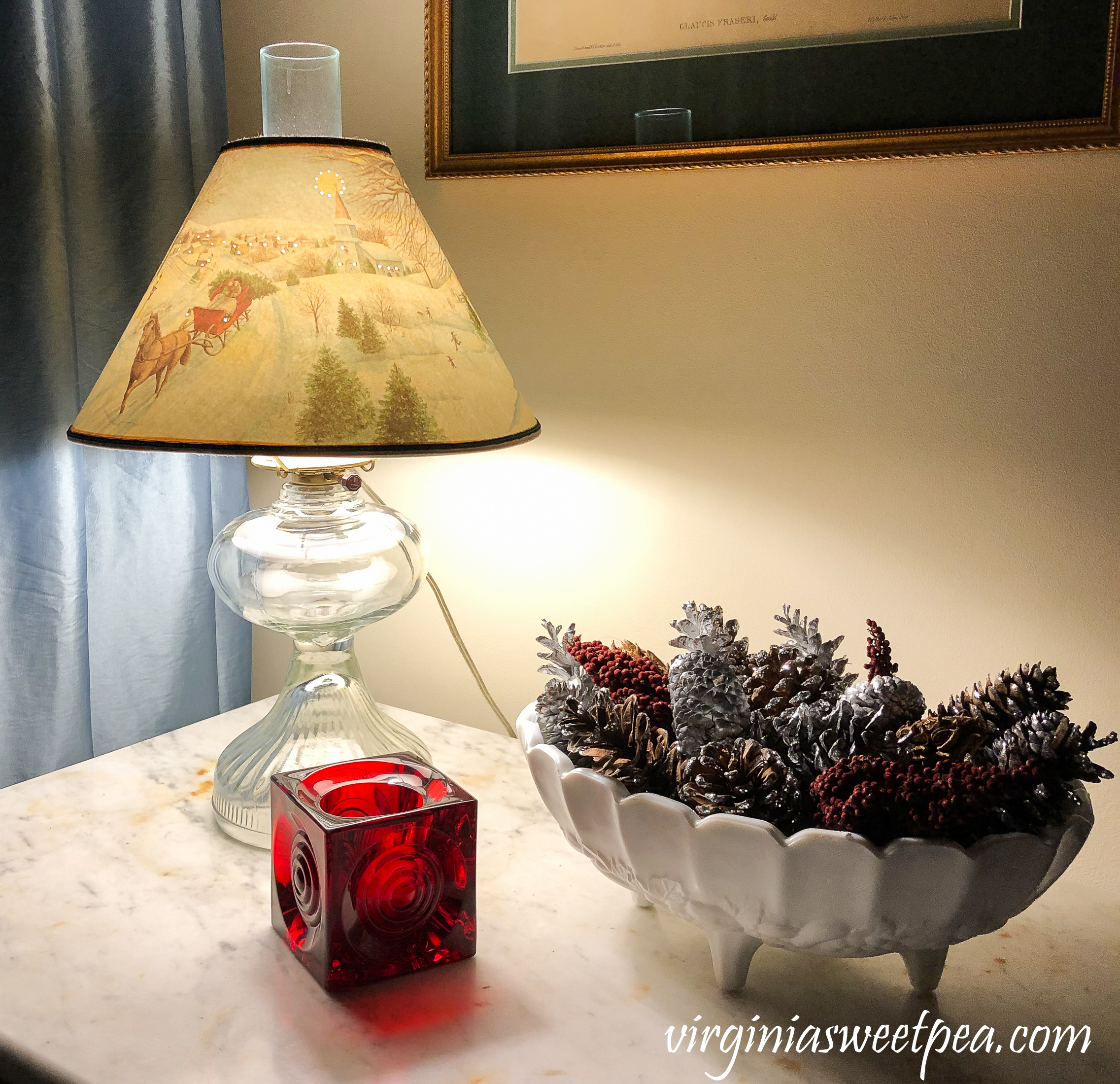 Vintage Christmas Vignette - Antique lamp with a Christmas shade, milk glass compote filled with natural items, and a Blenko candle holder.