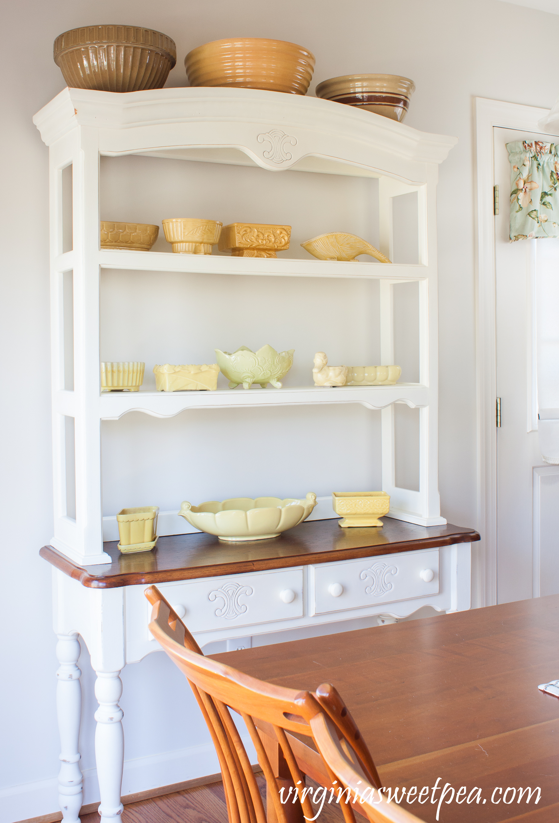 Farmhouse Hutch with Vintage Yellow Pottery - See a collection of vintage yellow pottery displayed on a farmhouse-style hutch. Vintage mixing bowls on top of the hutch add to the charm of this display. #vintage #vintagedecor #vintagepottery #farmhousedecor #USApottery #mccoy #mccoypottery #watts #cooksonpottery #abingdonpottery