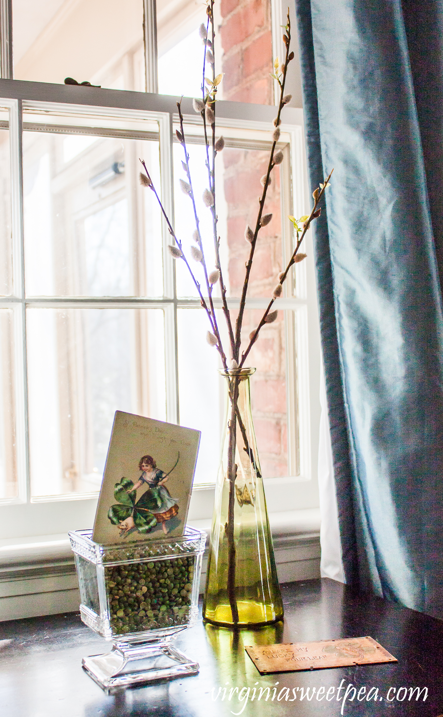 St. Patrick's Day vignette with a 1908 postcard, glass planter filled with green split pea, and a green vase with pussy willow. #stpatricksday #stpatricksdayvignette #stpatricksdaypostcard #vintagepostcard