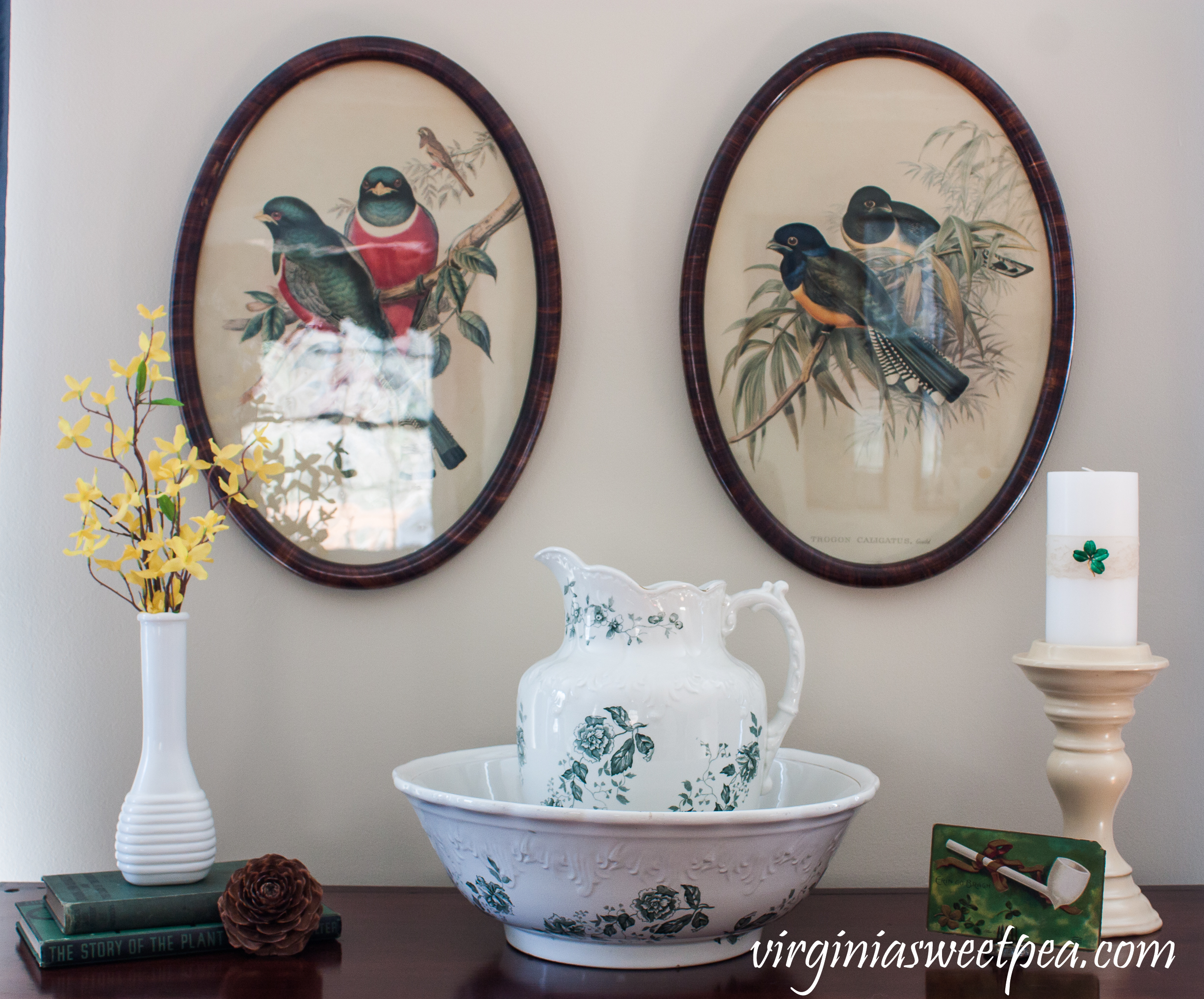 St. Patrick's Day Vignette with a A. U. Wilkinson, England, Royal Semi Porcelain Bowl and Pitcher; milk glass vase filled with Forsythia on vintage books, a candle decorated with a vintage four leaf clover pin and a vintage St. Patrick's Day postcard #vintage #vintagedecor #antiquebowlandpitcher #stpatricksdaydecor