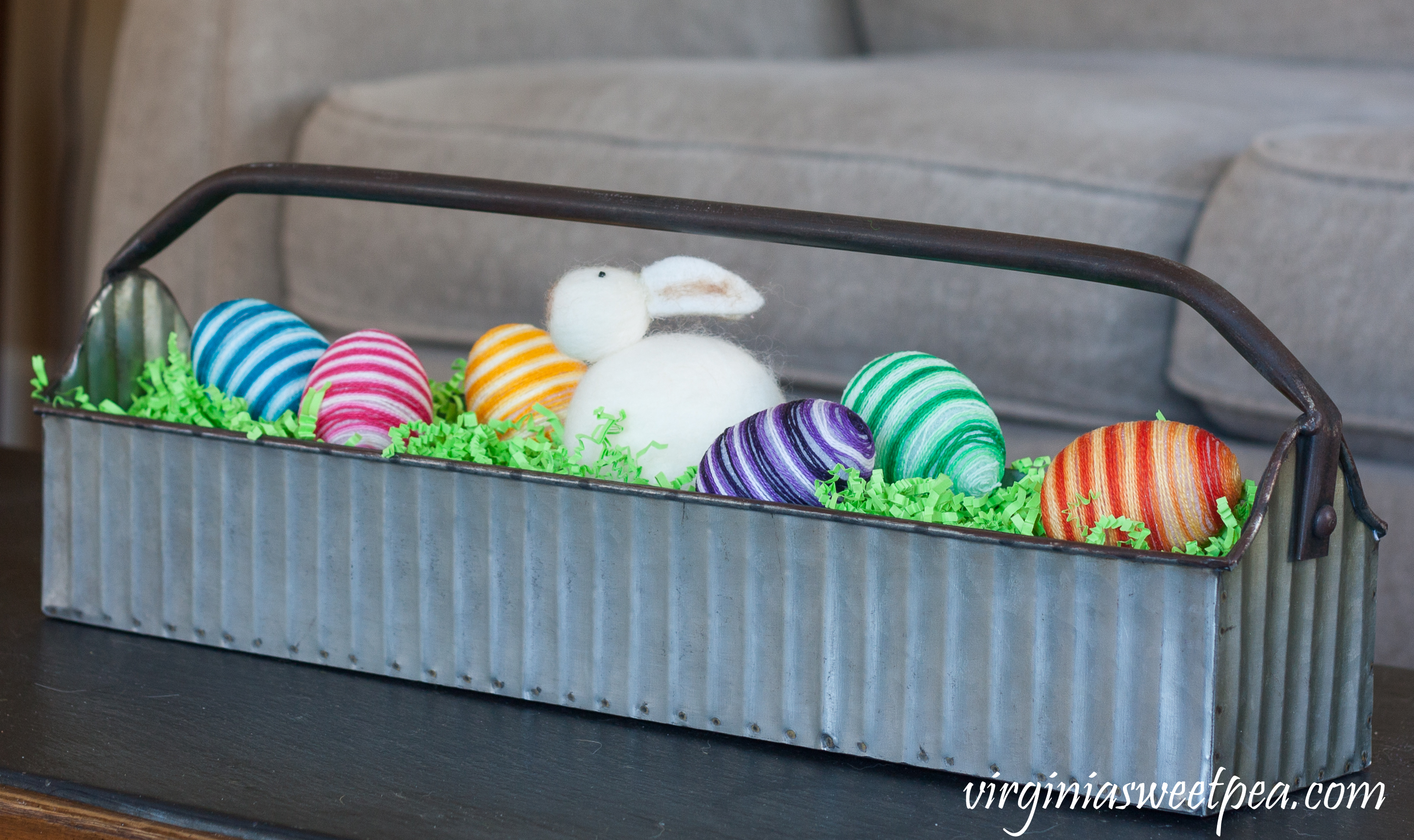 Metal tool caddy decorated for Easter with handmade striped eggs and a stuffed Easter rabbit.