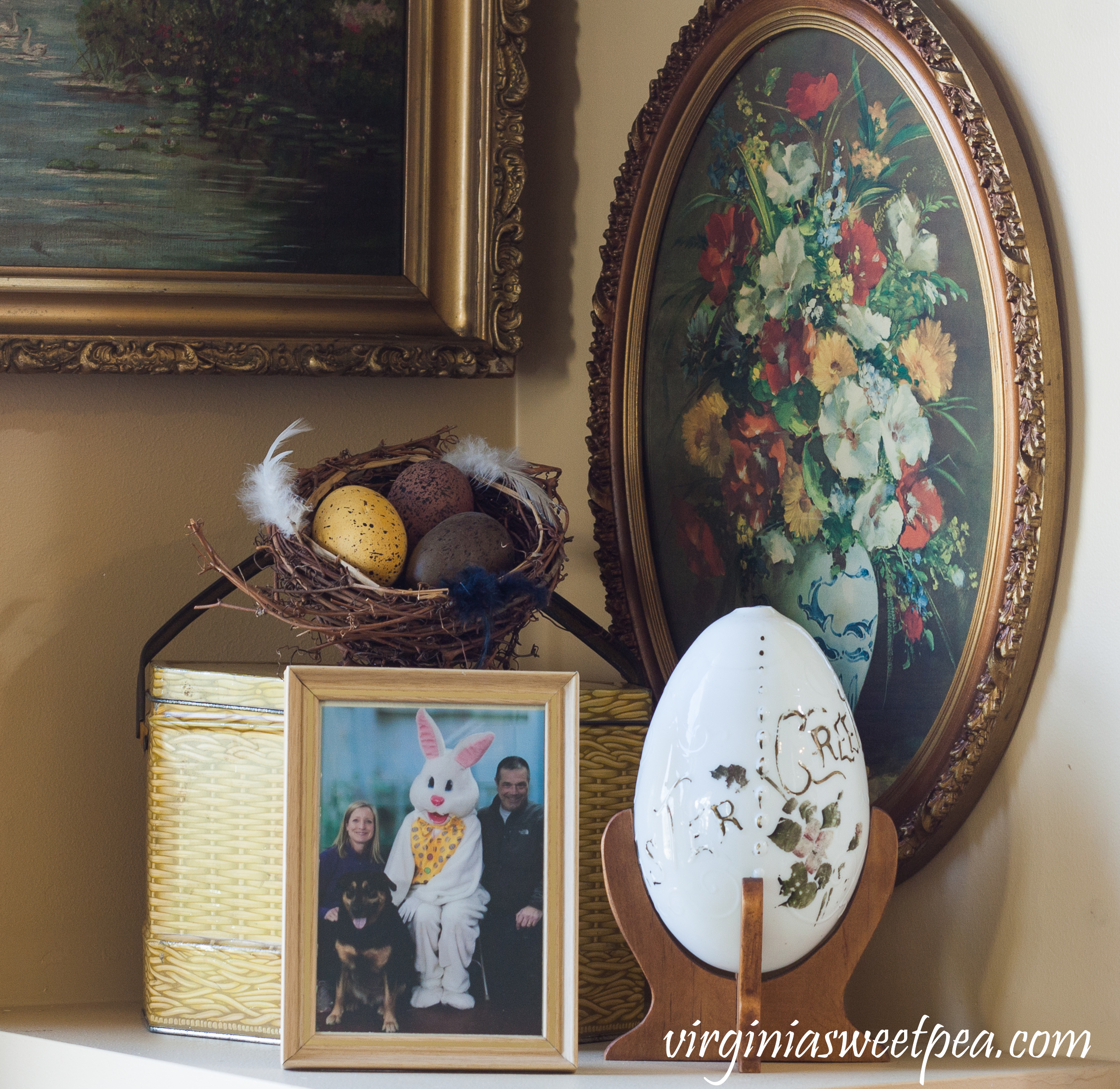 Easter Display with a vintage metal basket printed with a basketweave pattern, large china vintage egg printed with "Easter Greetings" and a family Easter picture