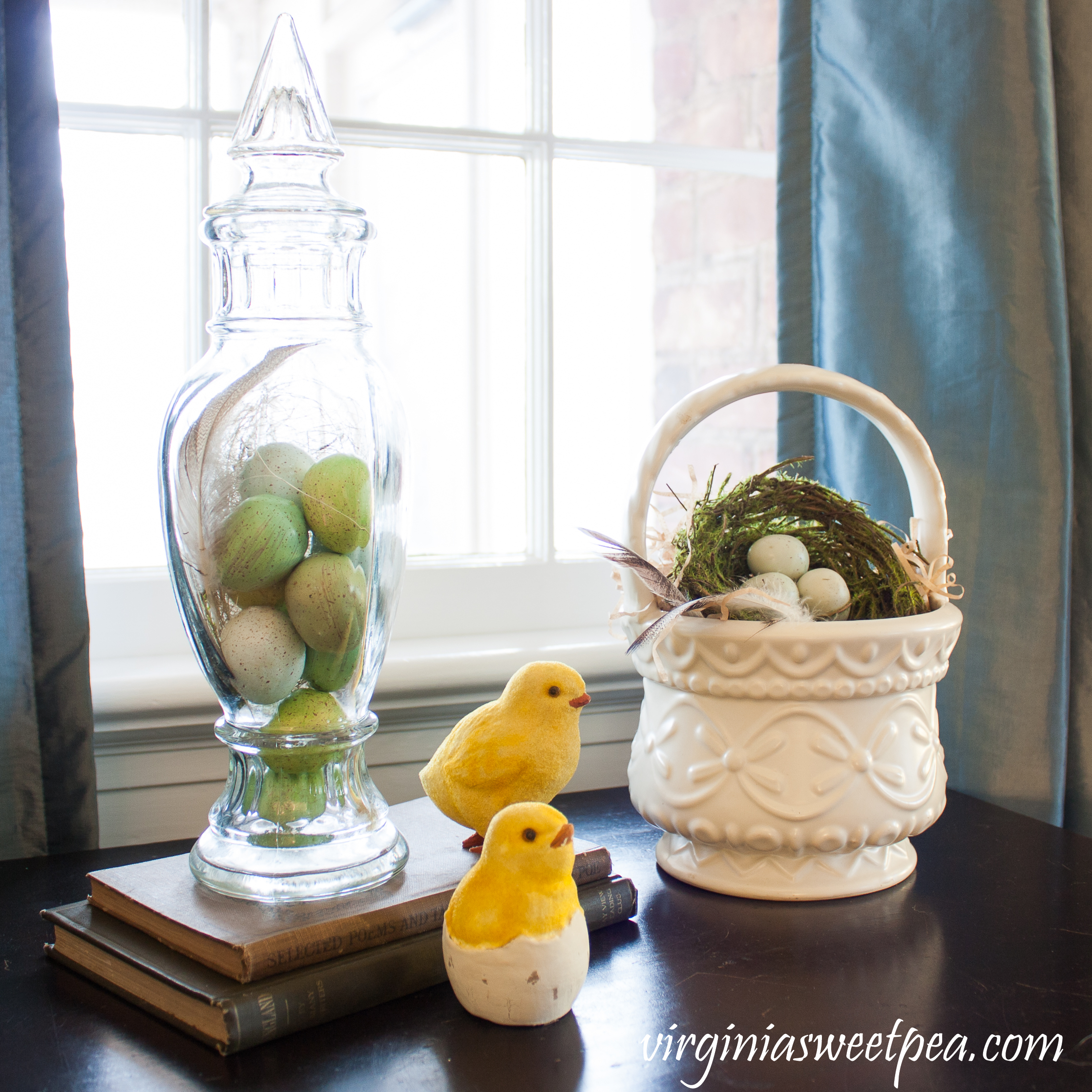 Easter vignette with eggs in a vintage glass candy holder, a nest in a Hull basket, chicks, and antique books #easterdecor #easterdecorations #vintagedecor #hull