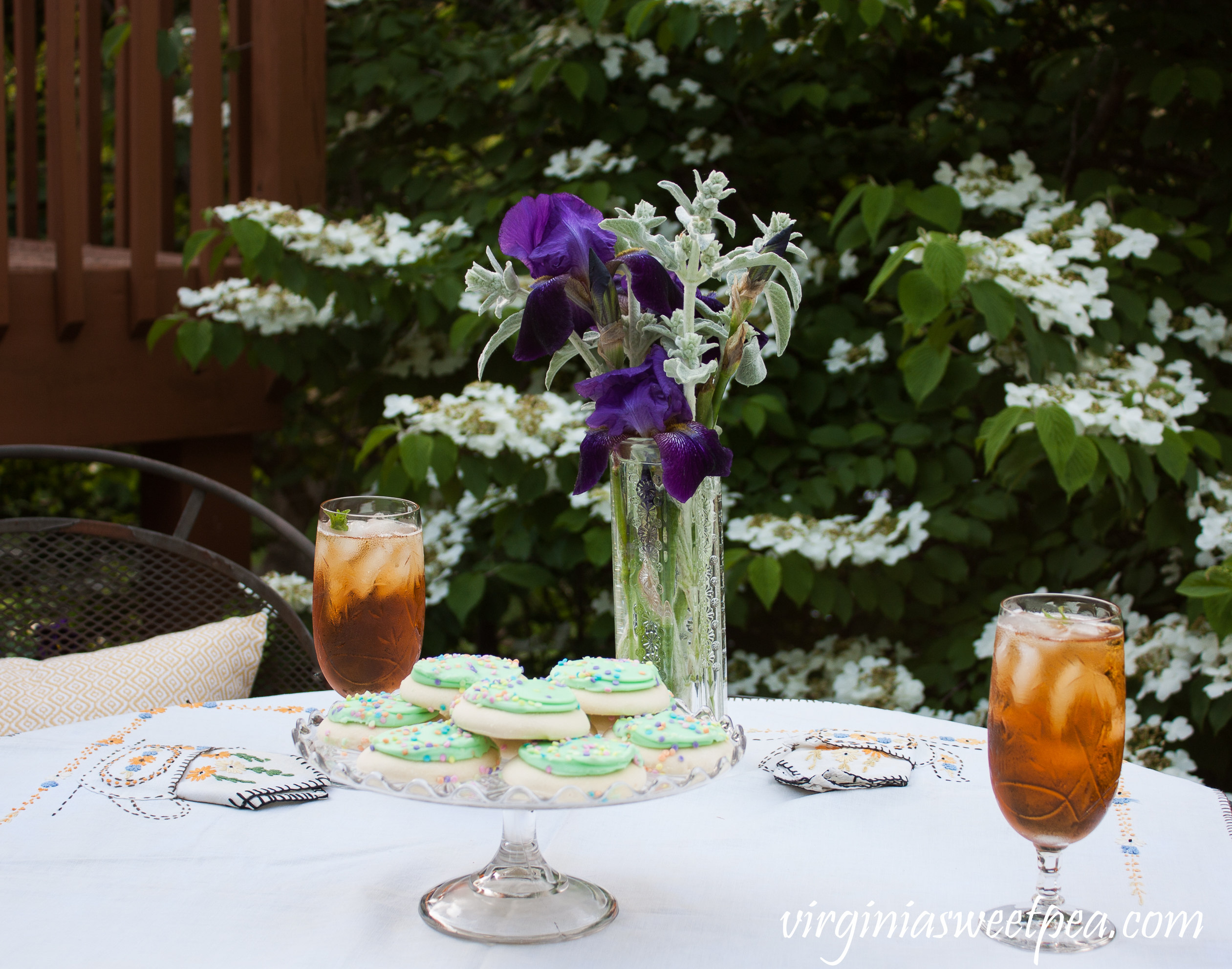 A Tea Party Featuring a 1930's Tea Themed Embroidered Tablecloth and vintage cake server, crystal, and flower vase.