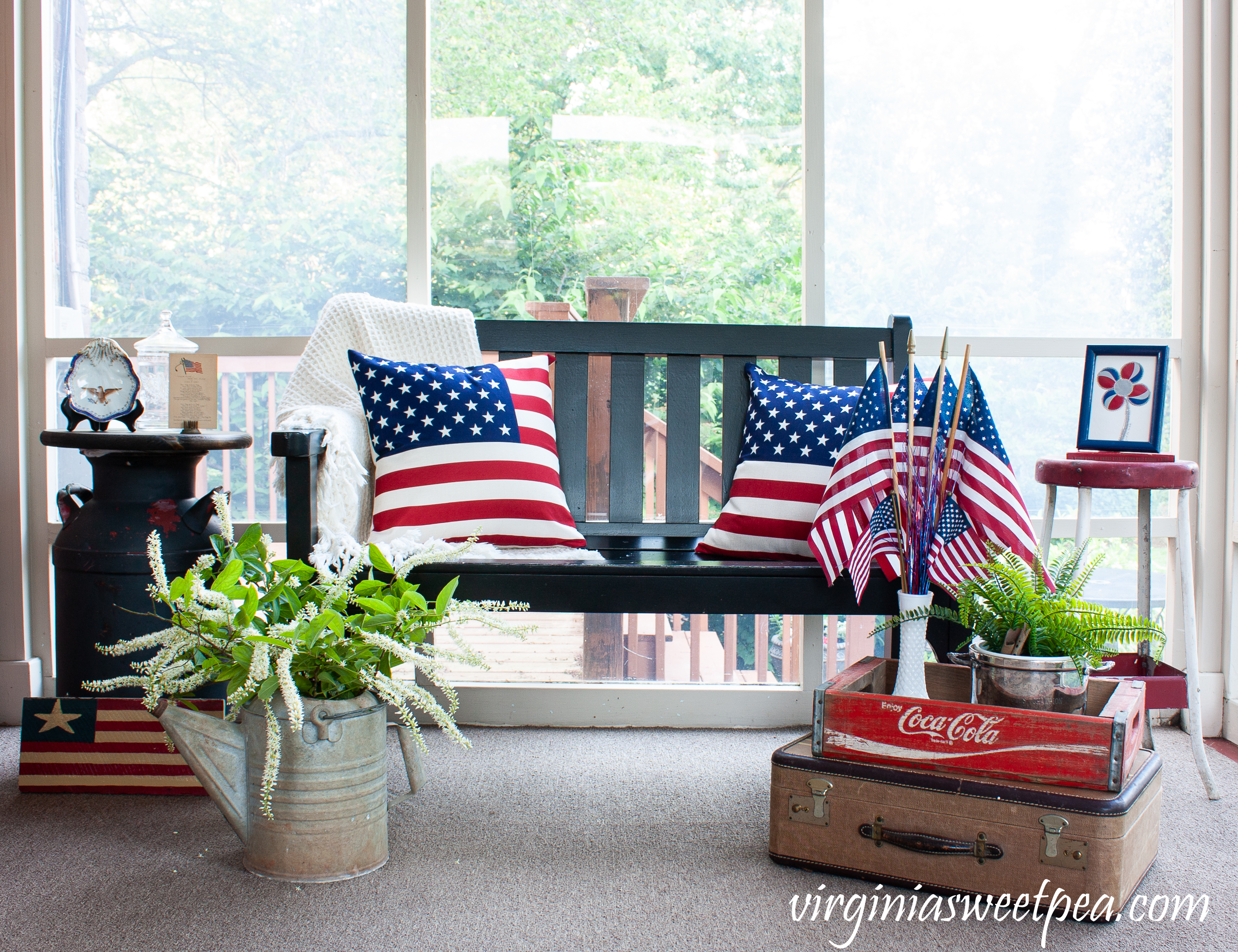 A porch is decorated patriotically with red, white, and blue and with vintage for July 4 and Memorial Day.