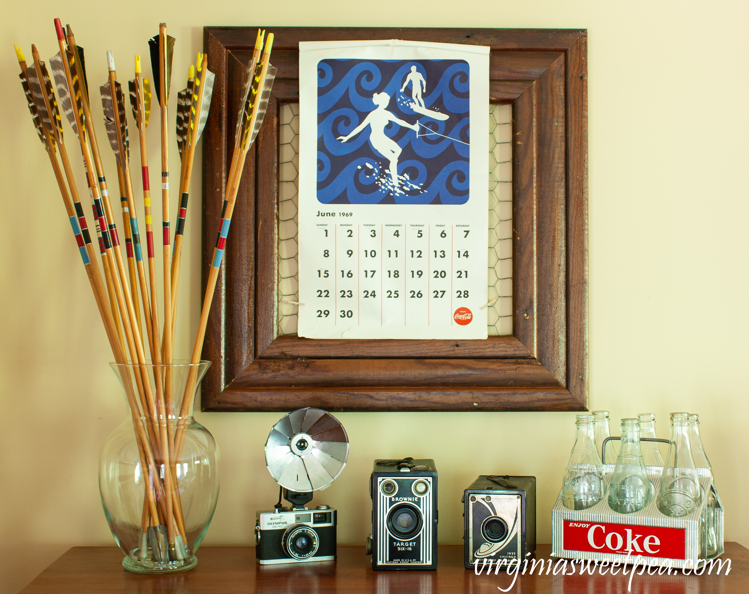 Summer Decorating with Vintage - Summer decor including vintage arrows, vintage cameras, a vintage Coke caddy, and a June Coca-Cola 1969 calendar page.