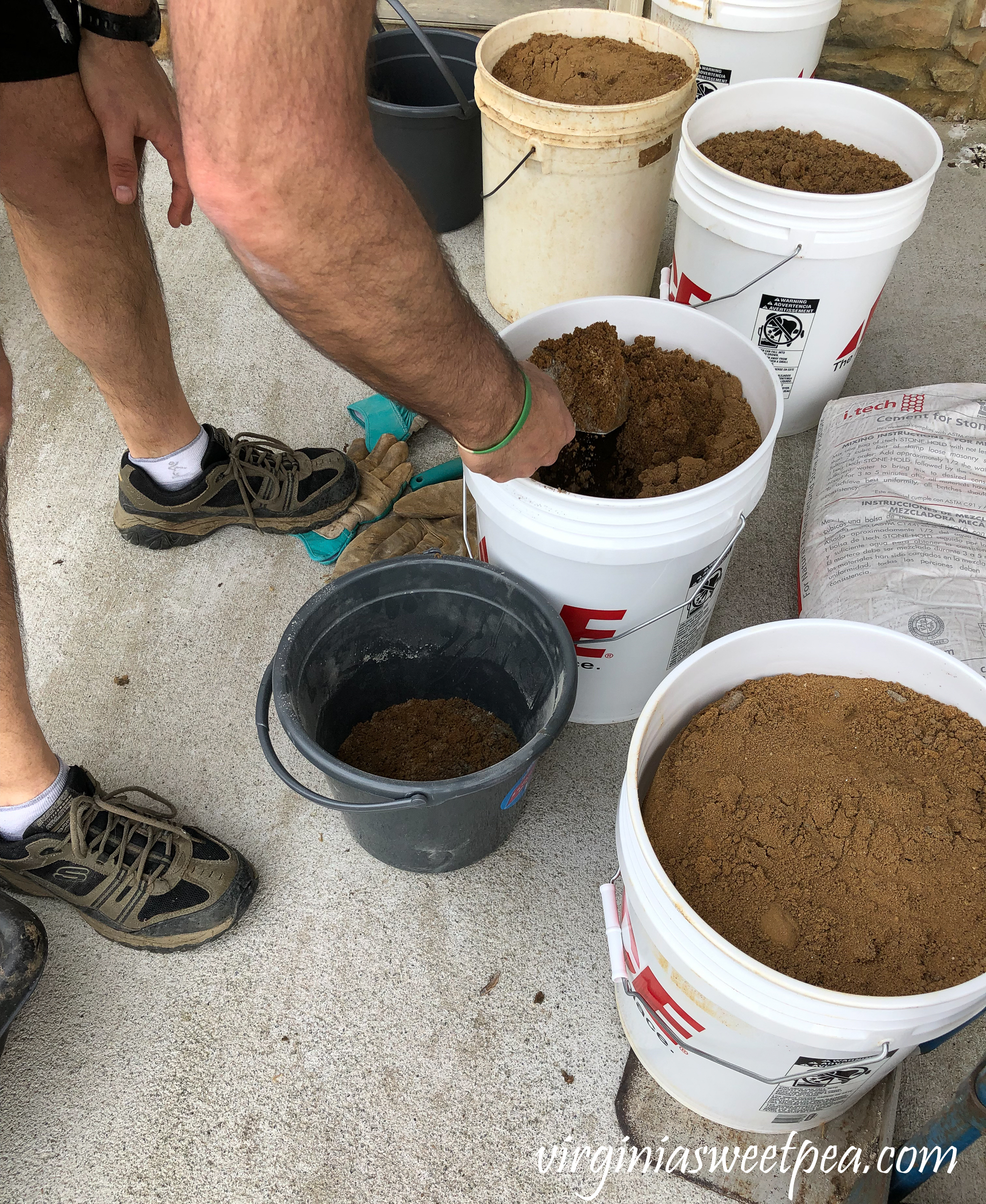 Mixing concrete to use to face a patio wall with stone veneer.