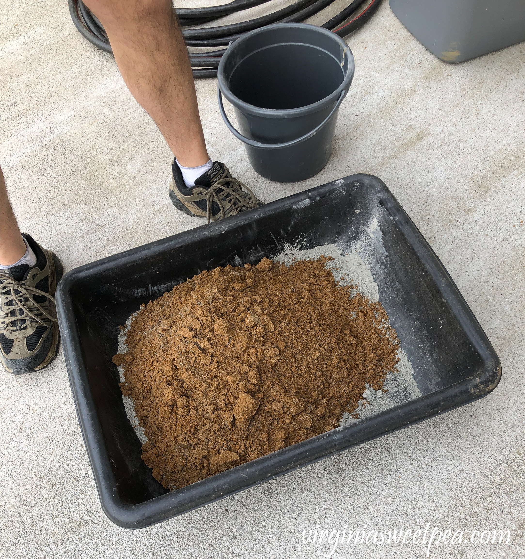 Mixing concrete to use to face a patio wall with stone veneer.