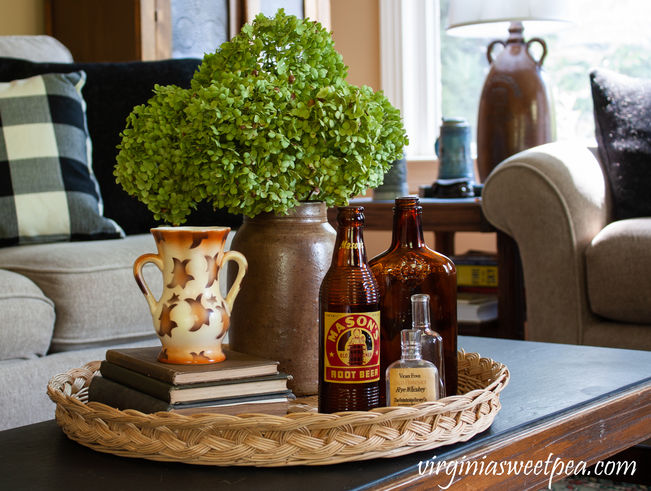 Fall coffee table decor with Hydrangea in a vintage crock, a stack of books with a vintage vase, and three vintage bottles