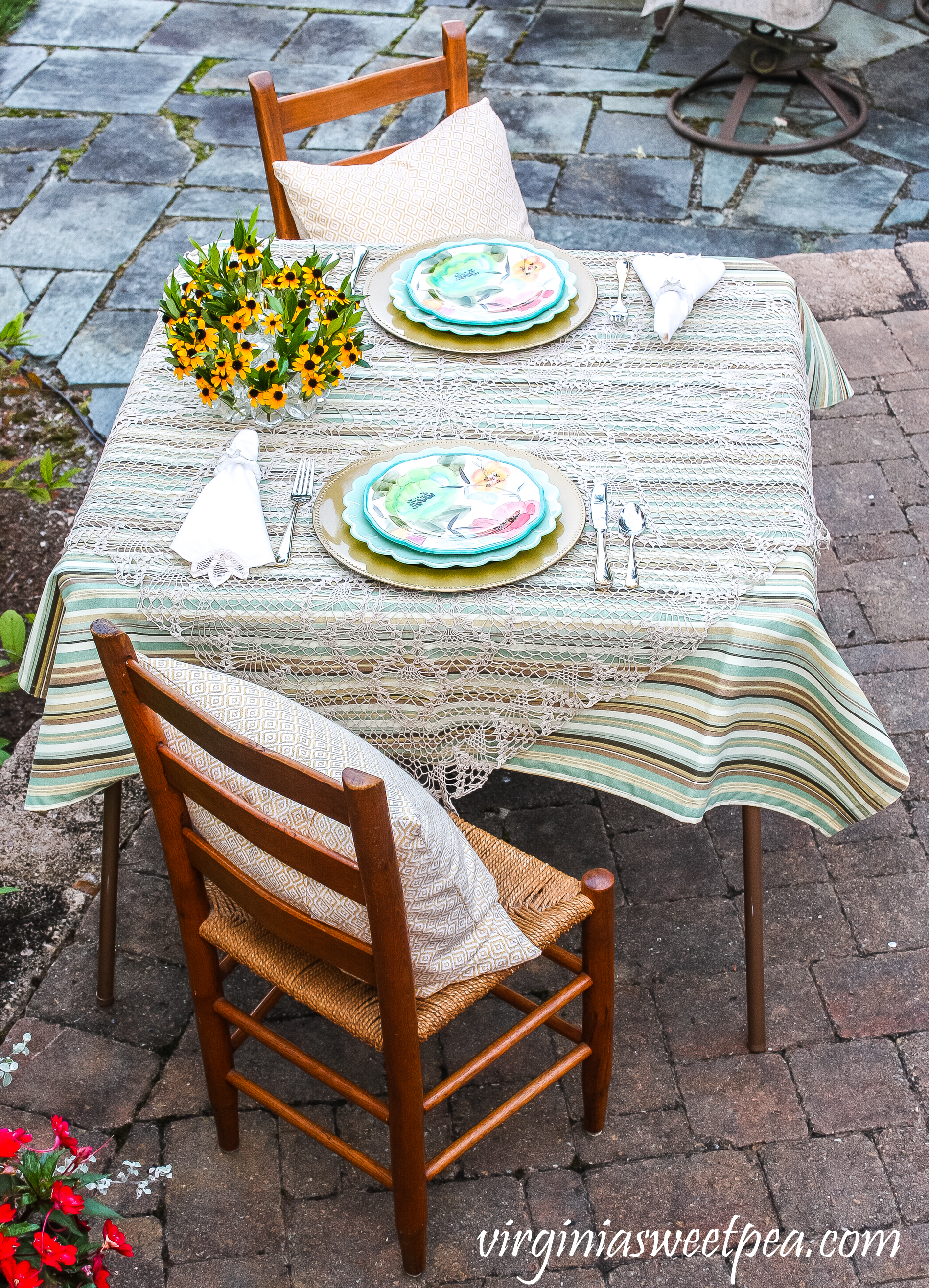 Summer tablescape set in a yard with Pioneer Woman dishes and a floral centerpiece.
