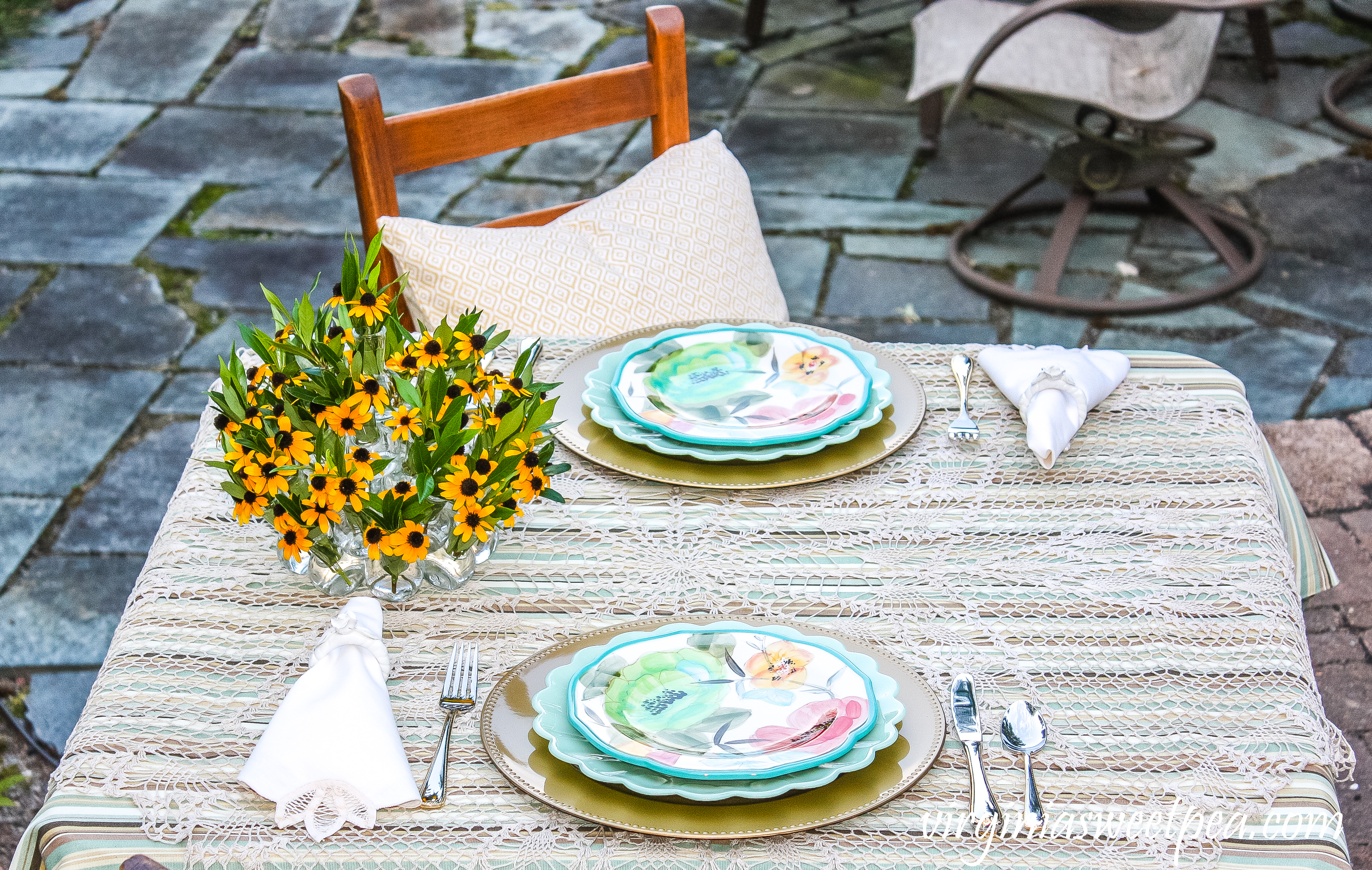 Summer tablescape set in a yard with Pioneer Woman dishes and a floral centerpiece.