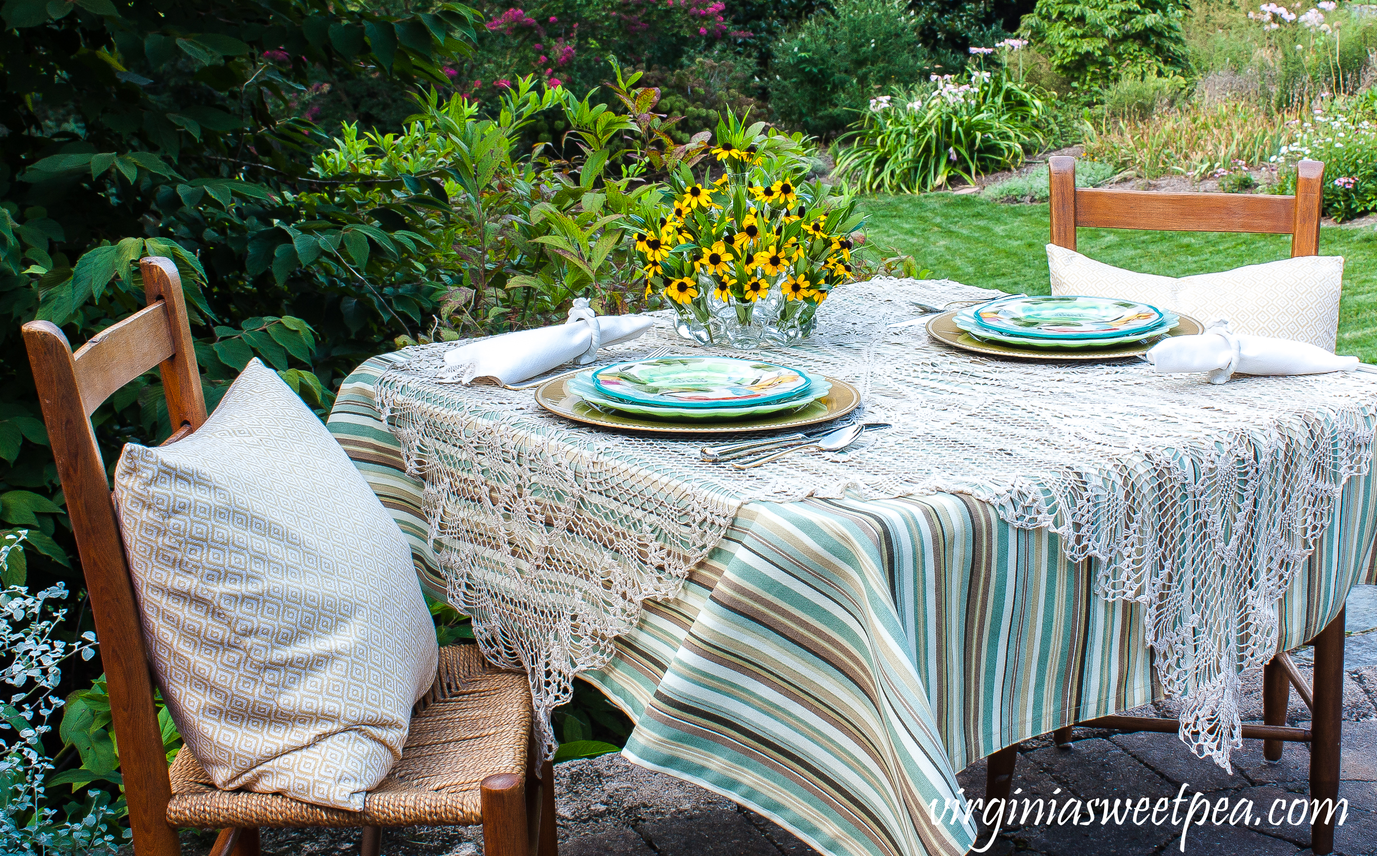 Summer tablescape set in a yard with Pioneer Woman dishes and a floral centerpiece.