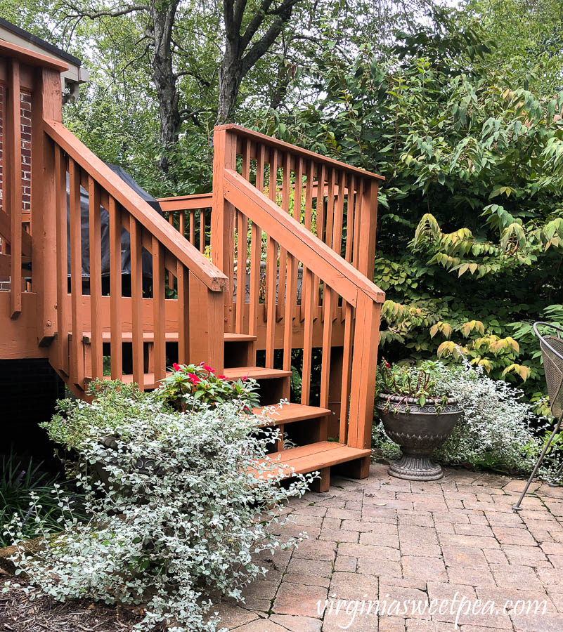 Two pots planted with summer annuals flanking a deck. Annuals are tired after a summer of growth.