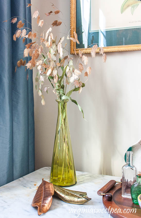 River Oats in a vintage green vase with a gold and a copper metallic Magnolia leaves