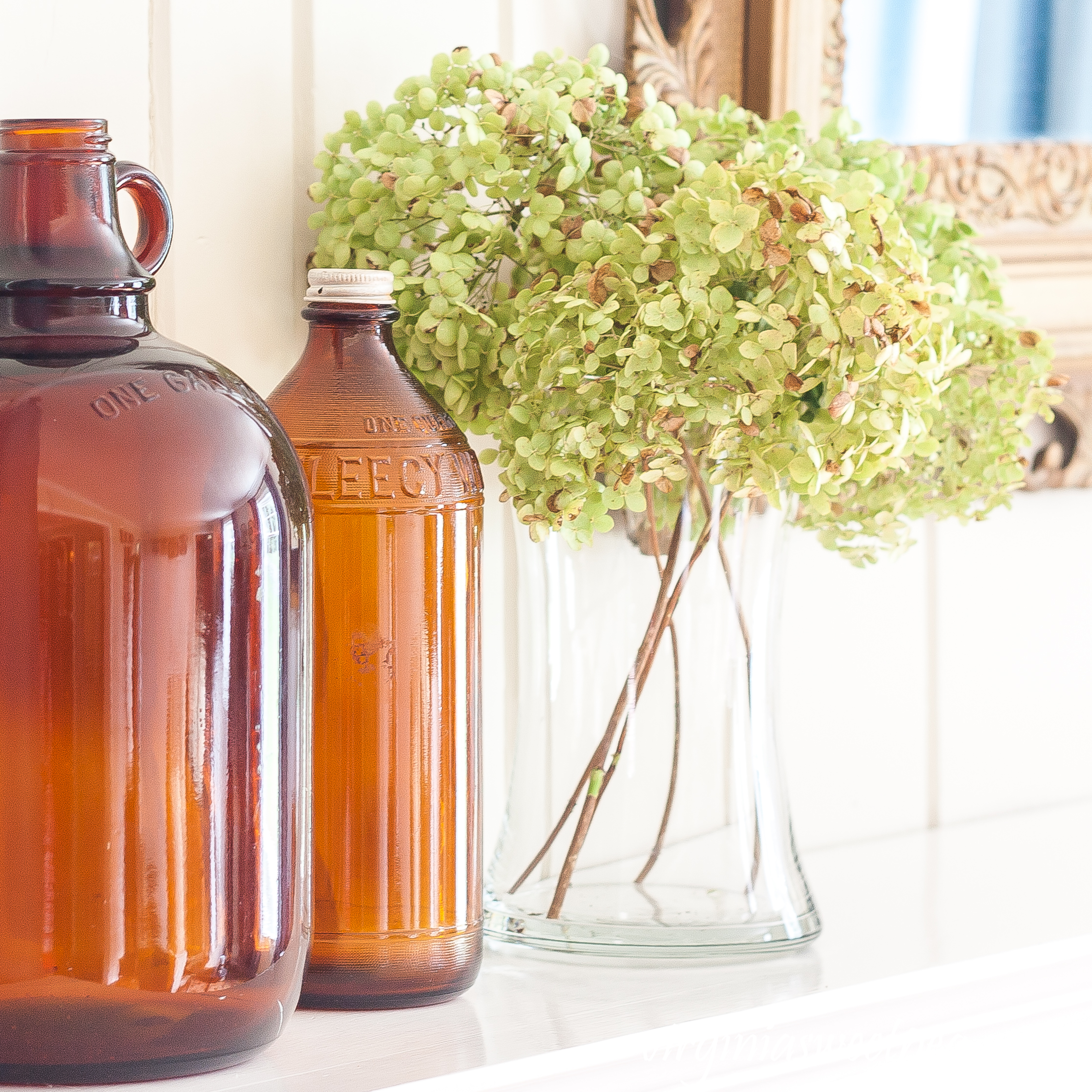 Mantel decorated for early fall with Hydrangea and brown glass bottles.