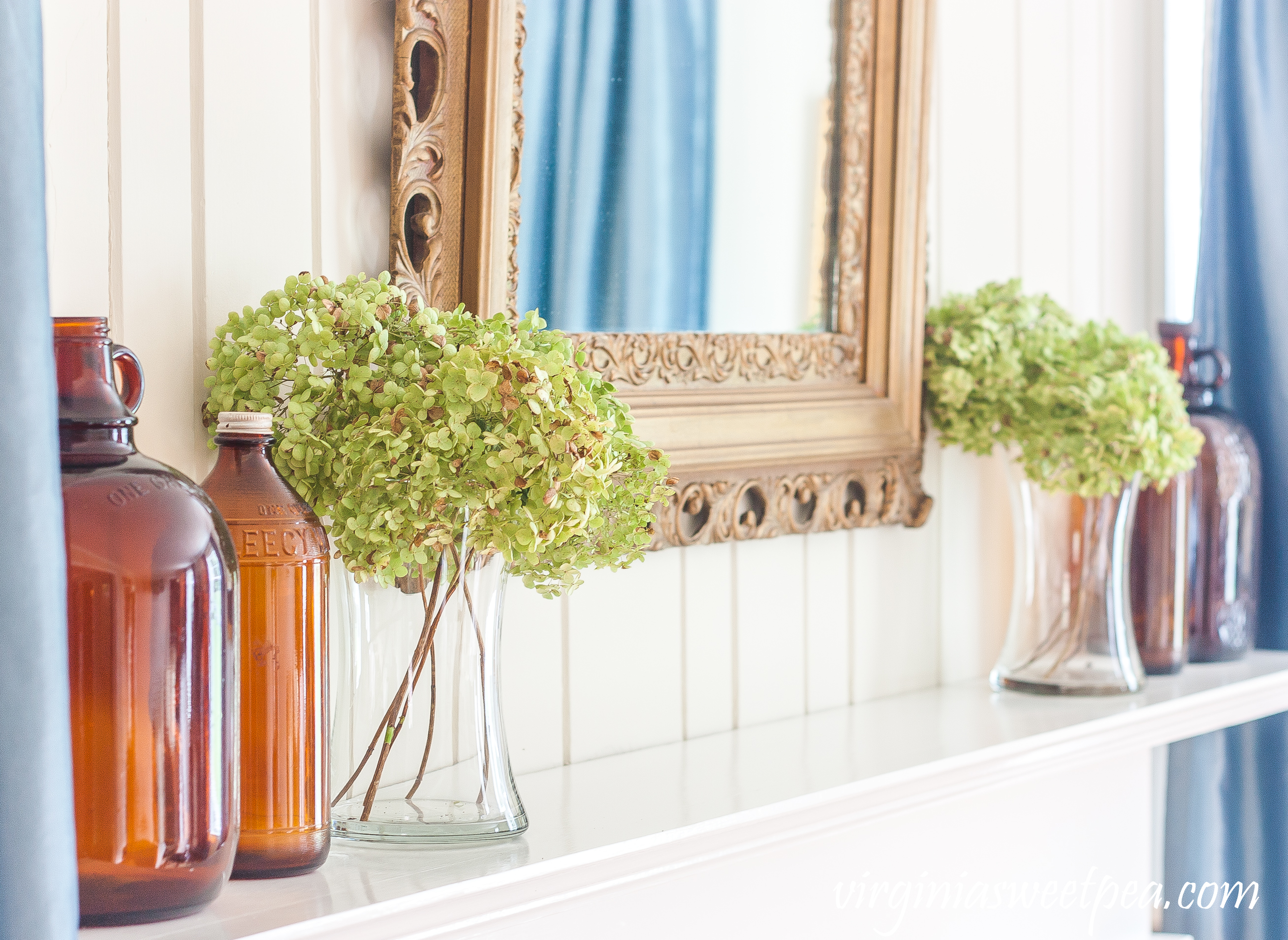 Mantel decorated for early fall with Hydrangea and brown glass bottles.