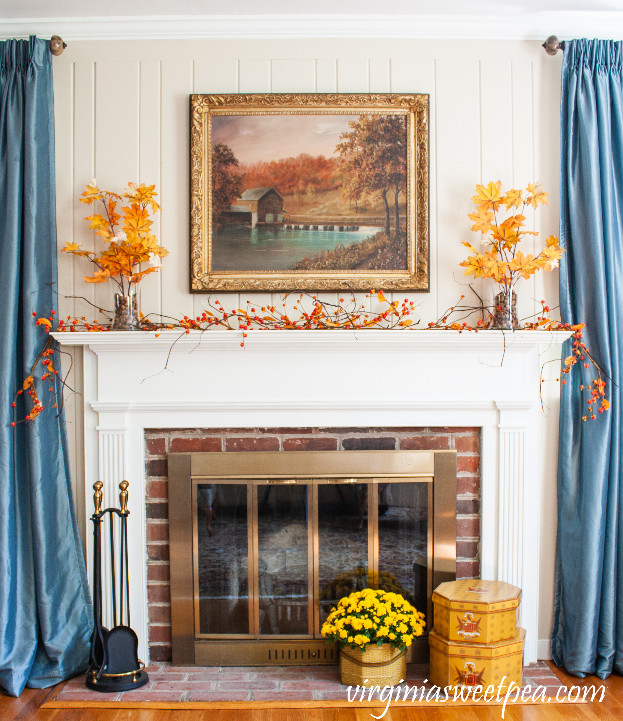 Traditional fall mantel with mill painting, bittersweet, leaves anchored in glass vases with acorns