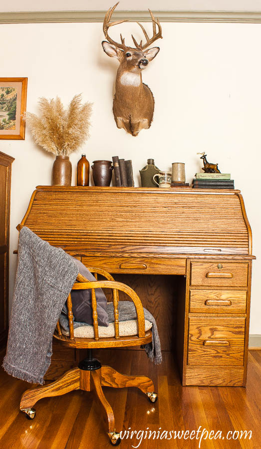 A roll top oak desk is decorated with vintage with a masculine and cabin theme.