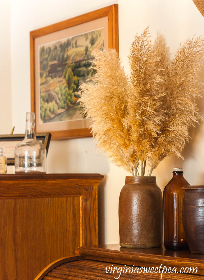 Pampas grass in an antique crock with an amber vintage Clorox bottle and a Emlyn Edwards painting.