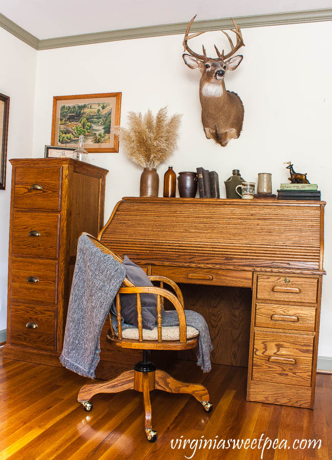 A roll top oak desk is decorated with vintage with a masculine and cabin theme.