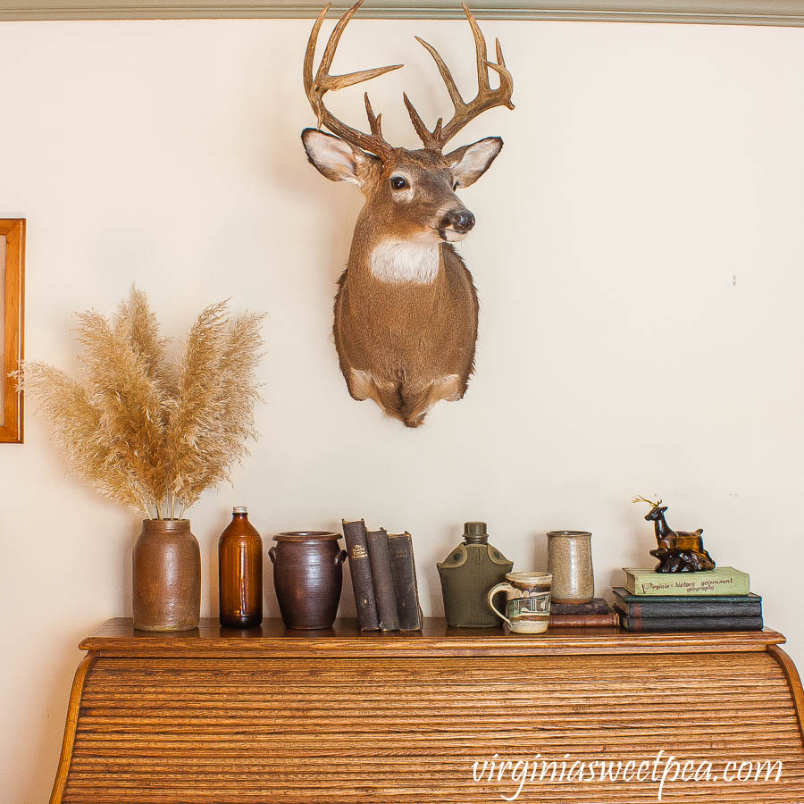 A roll top oak desk is decorated with vintage with a masculine and cabin theme.