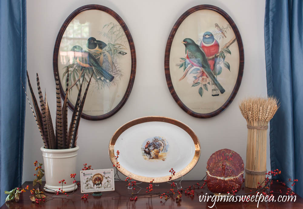 Thanksgiving Decor with Vintage - An antique chest is decorated with a vintage turkey platter, crock filled with pheasant feathers, a vintage Thanksgiving postcard, a wheat sheaf, and a vintage turkey lidded dish.