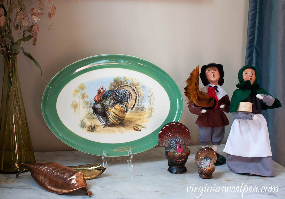 Thanksgiving decor using a vintage turkey platter, Byers' Choice pilgrims, and vintage turkey candles.