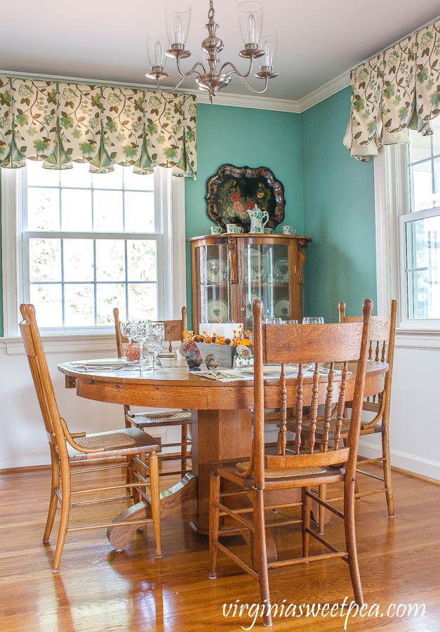 Antique oak dining room table and chairs with a table set for Thanksgiving.