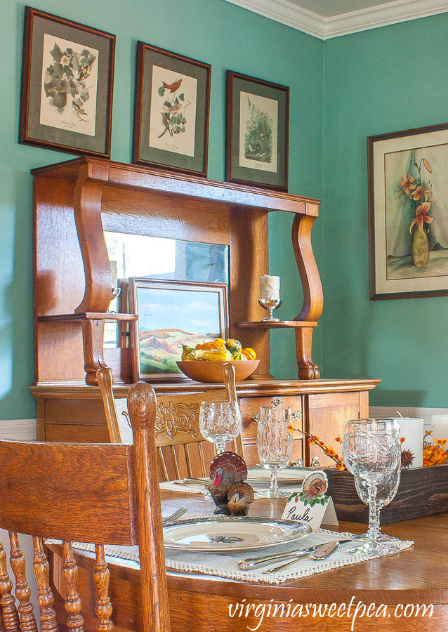 Thanksgiving table set on an oak table with an oak buffet in the background.