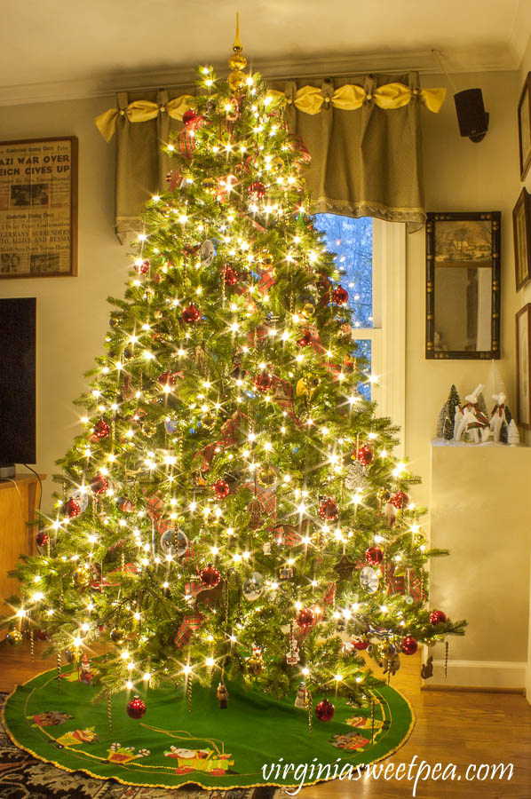 Family room Christmas tree at night decorated with ornament collected over 25 years.