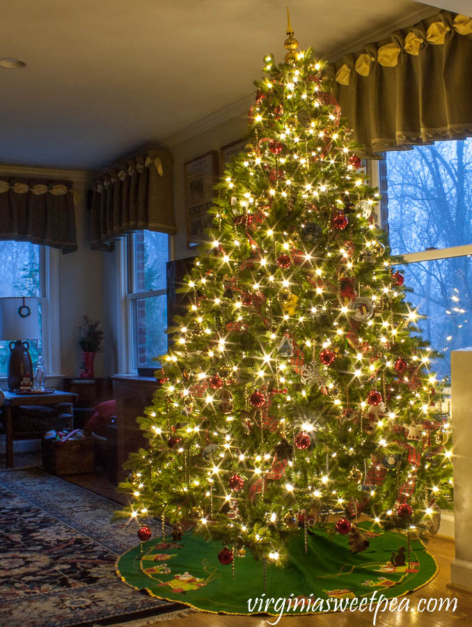 Family room Christmas tree at night decorated with ornament collected over 25 years.