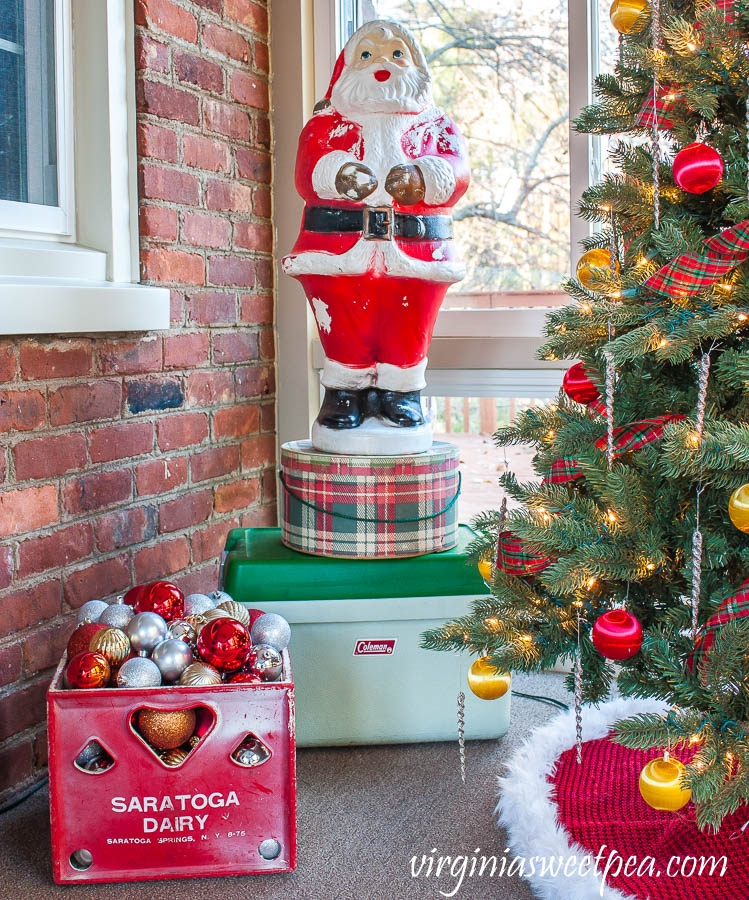 A Very Vintage Christmas on the Porch - Blow mold Santa, vintage plaid hat box, vintage Coleman cooler, and a vintage Saratoga Dairy milk crate filled with ornaments.