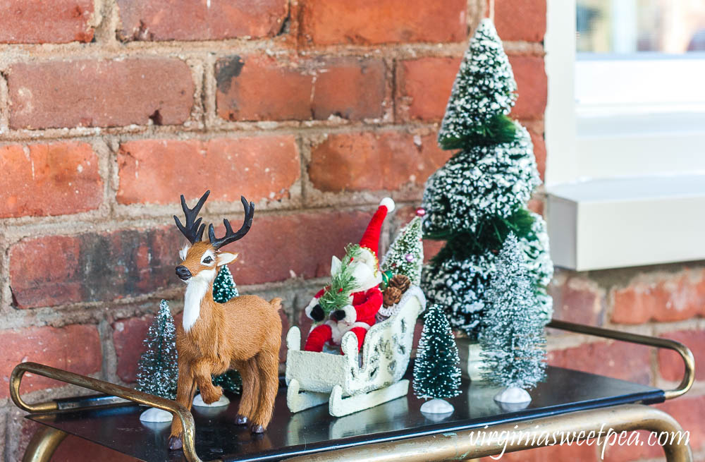 Byer's Choice reindeer with a Santa in his sled from the Vermont Country Store traveling through a forest of bottlebrush trees