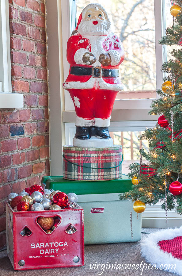 A Very Vintage Christmas on the Porch - Blow mold Santa, vintage plaid hat box, vintage Coleman cooler, and a vintage Saratoga Dairy milk crate filled with ornaments.